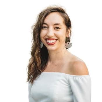 a woman in a white top smiling at the camera.