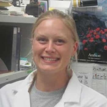 a woman in a lab coat is smiling for the camera.