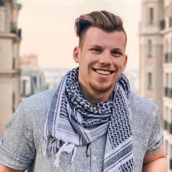 a man wearing a scarf standing in front of a building.