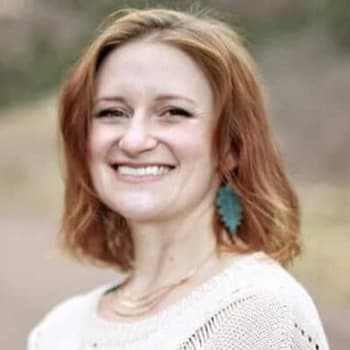 a woman with red hair wearing a white sweater.