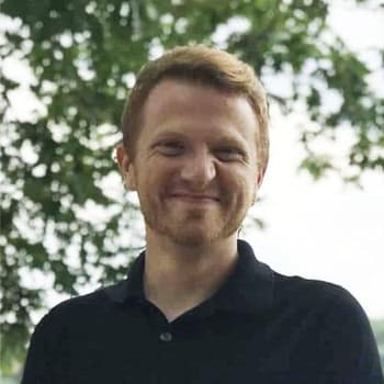 a man in a black shirt smiling at the camera.