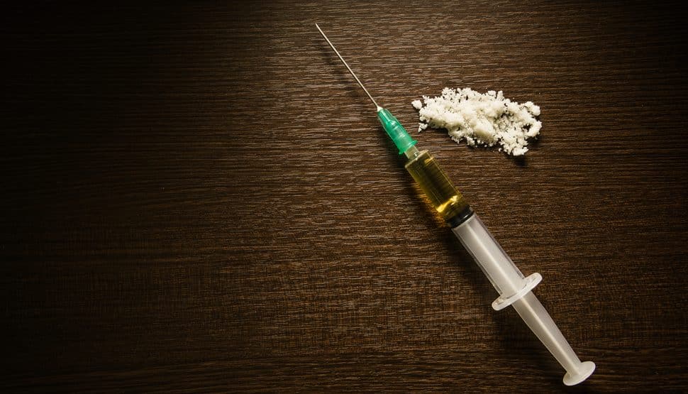 a bottle of white substance sitting next to a needle on a table.