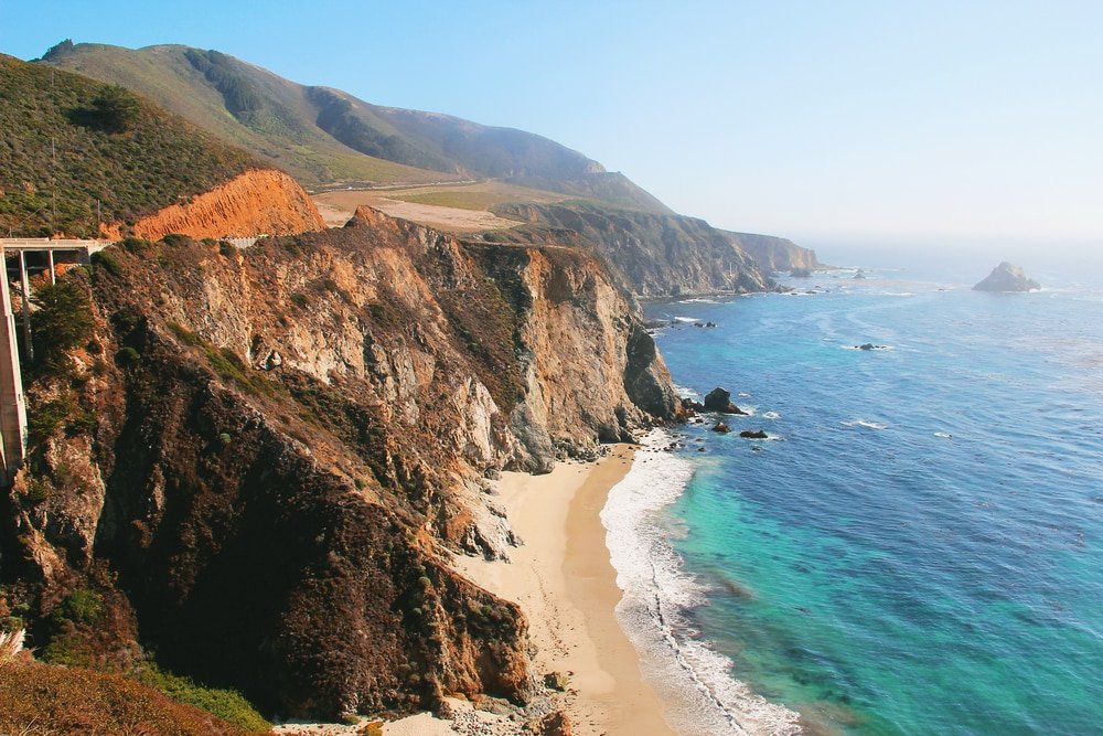 a view of a highway going over a cliff next to the ocean.