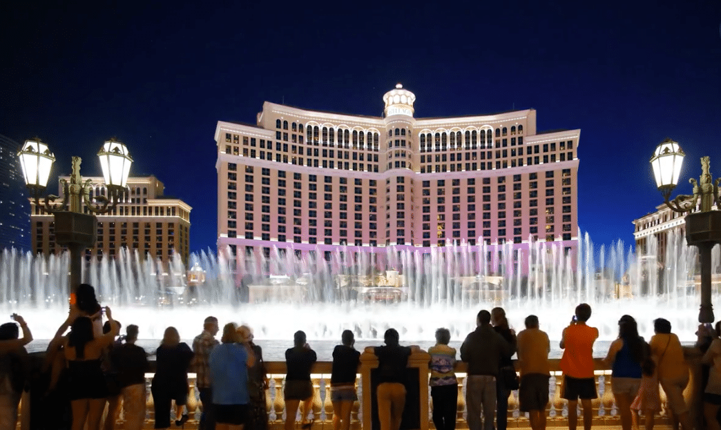 a group of people standing in front of a fountain.