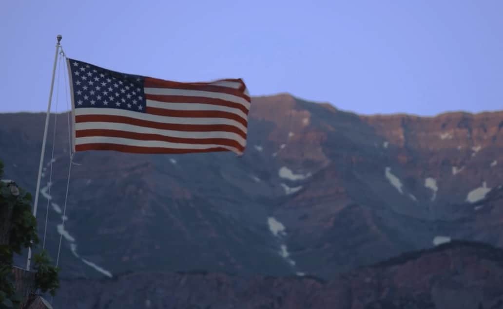 an american flag flying in front of a mountain.