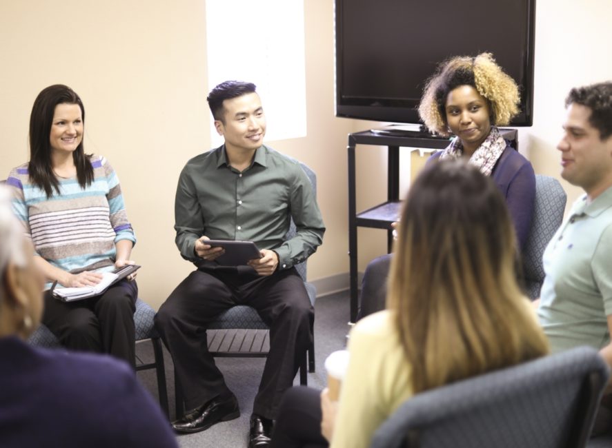 a group of people sitting around each other in a room.