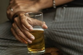 a person holding a glass of beer on a couch.