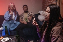 a woman sitting on a couch smoking a cigarette.