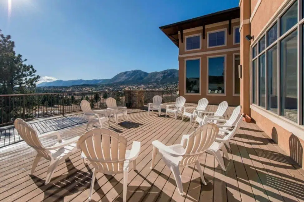 a deck with white chairs and a view of the mountains.