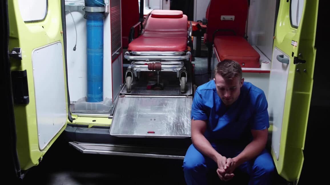 a man sitting in front of an ambulance.